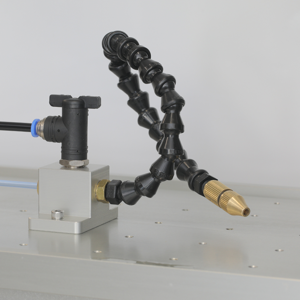 Adjustable mist nozzle clamped to the spindle of an NS CNC machine, aimed at the tool tip in the cutting zone