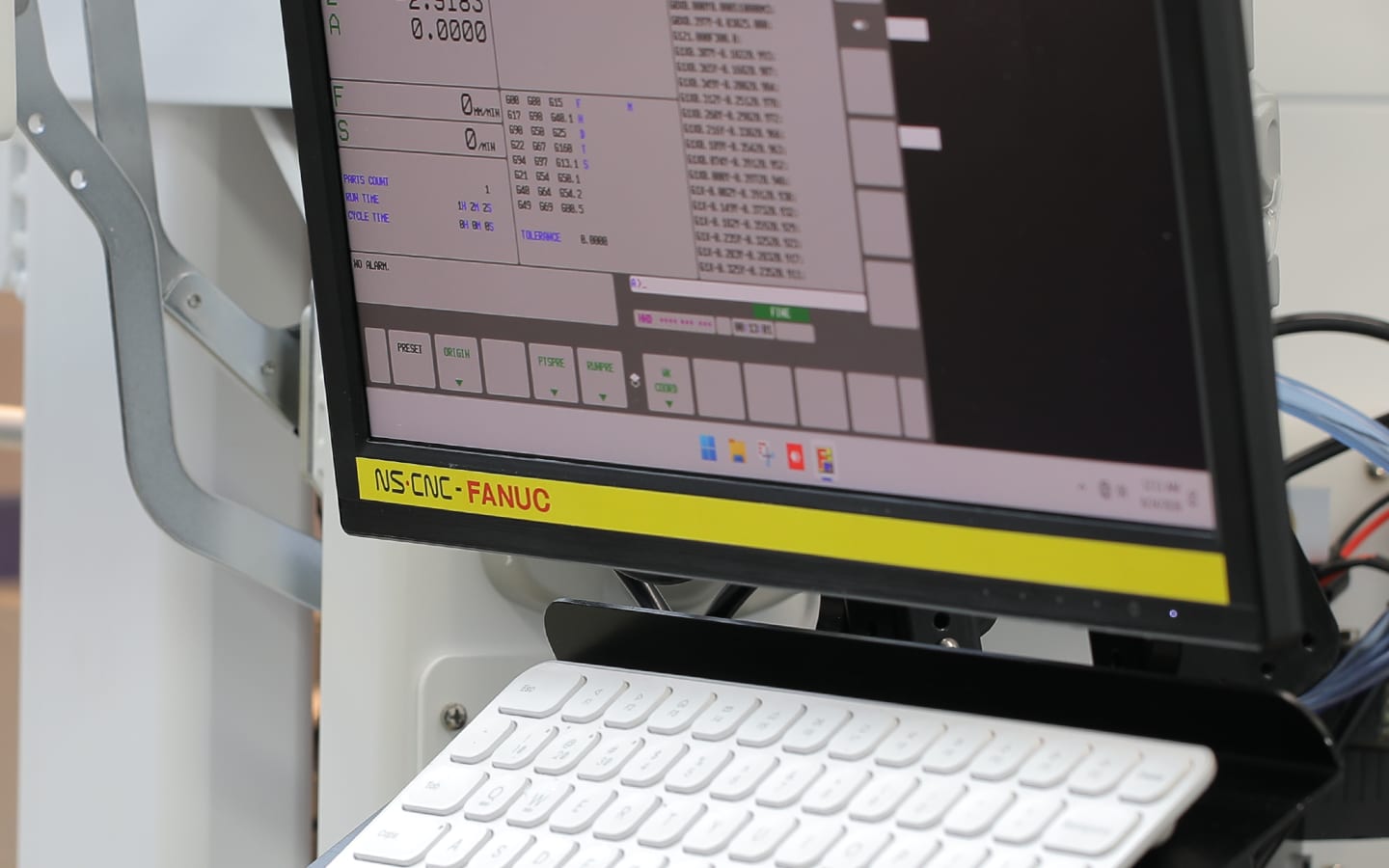 NS CNC monitor branded NS·CNC · FANUC, showing the FANUC control interface with position readout, program listing, and soft-key menu, keyboard below