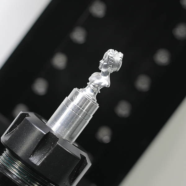 A miniature bust milled in aluminum, still on its stock held in the collet